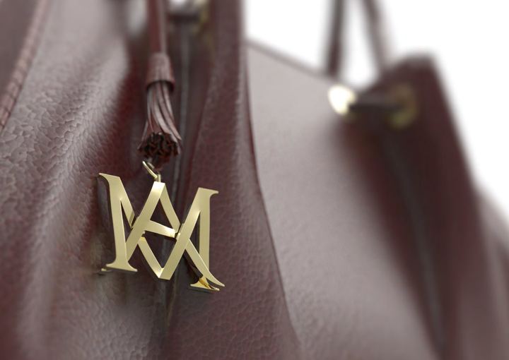 Gold MA monogram charm on a burgundy bag
