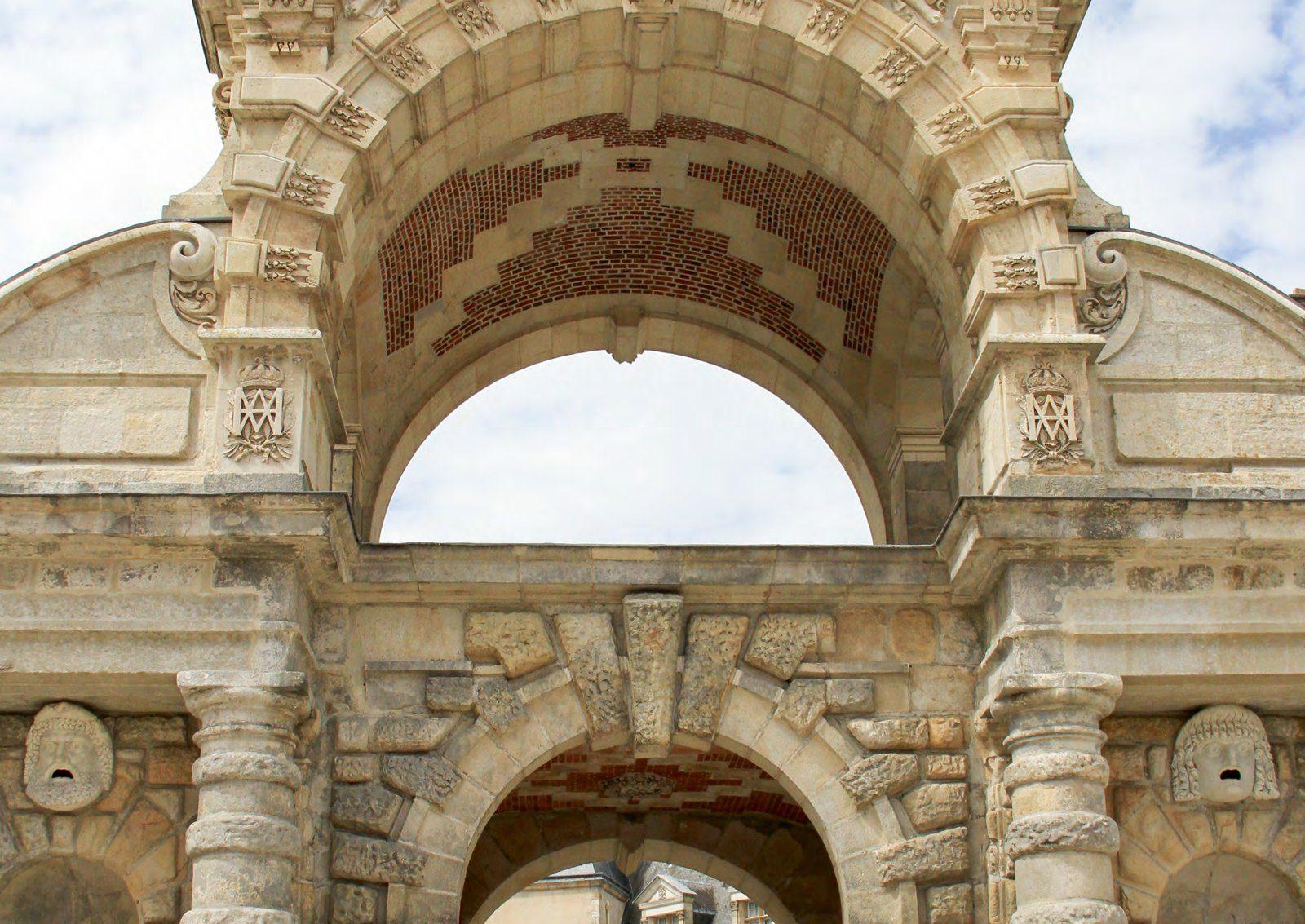 Ein steinerner Torbogen im Schloss Fontainebleau, darüber ihr eingemeißeltes Monogramm